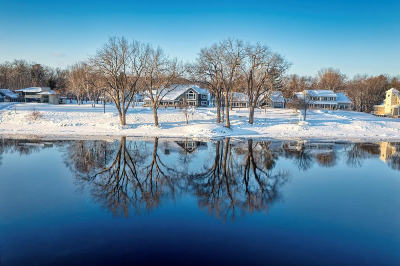 a snowy landscape with trees on the shoreline