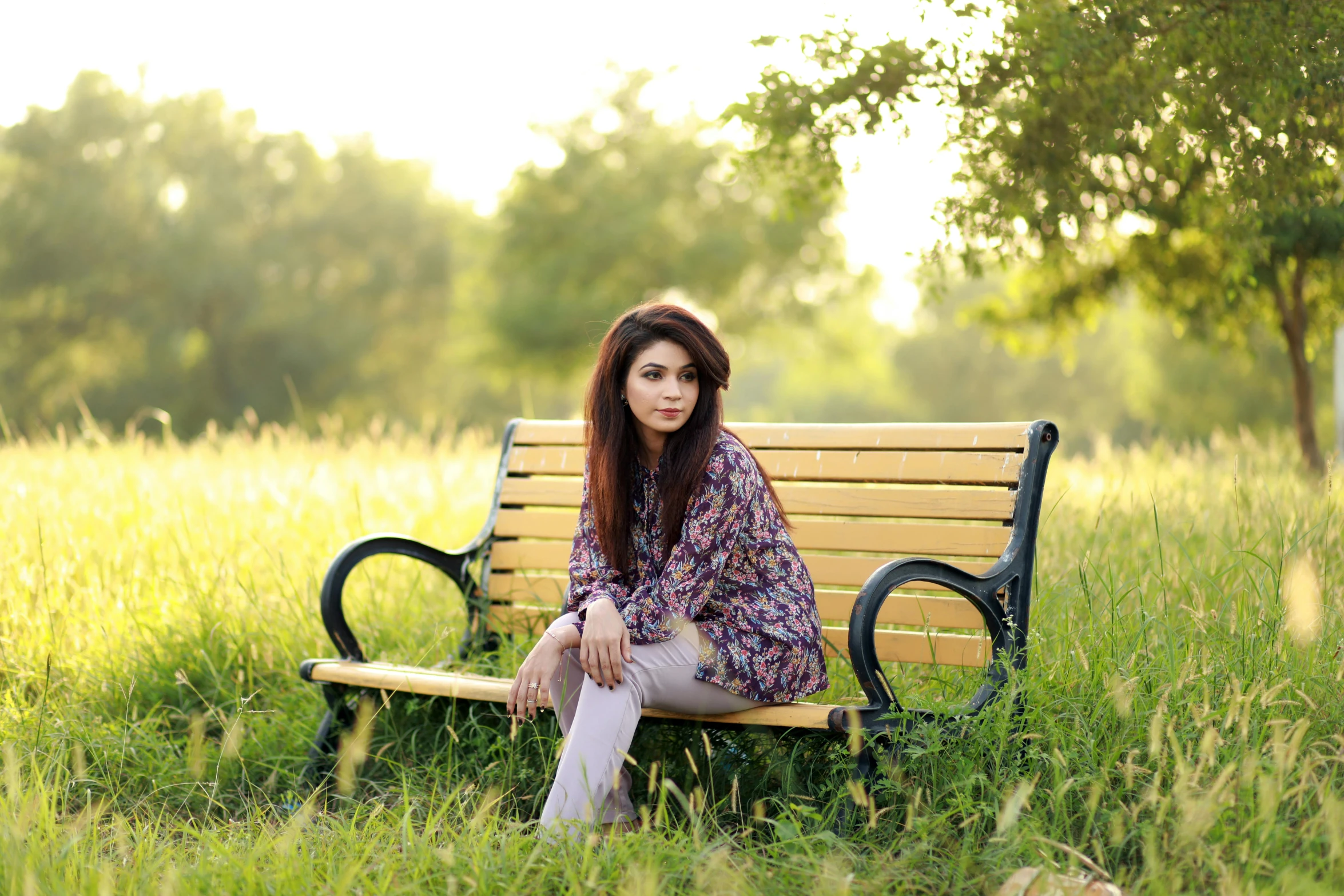 woman in patterned shirt sitting on a park bench