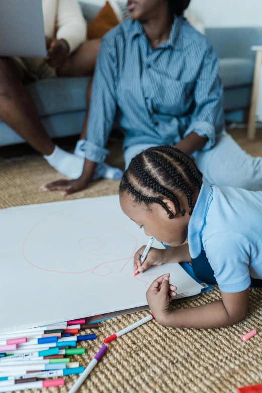 a little boy sitting in front of a white paper