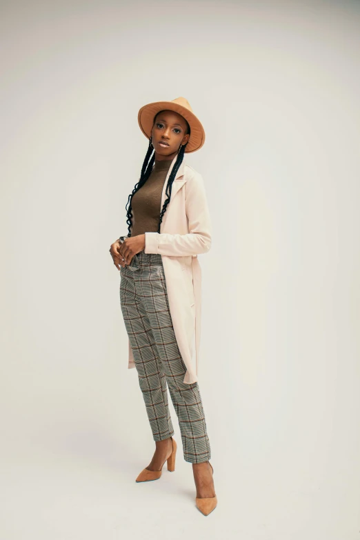 an african american woman poses in a long coat and patterned pants