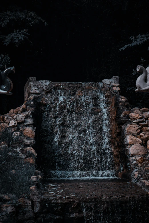 some statues sit near a stream of water