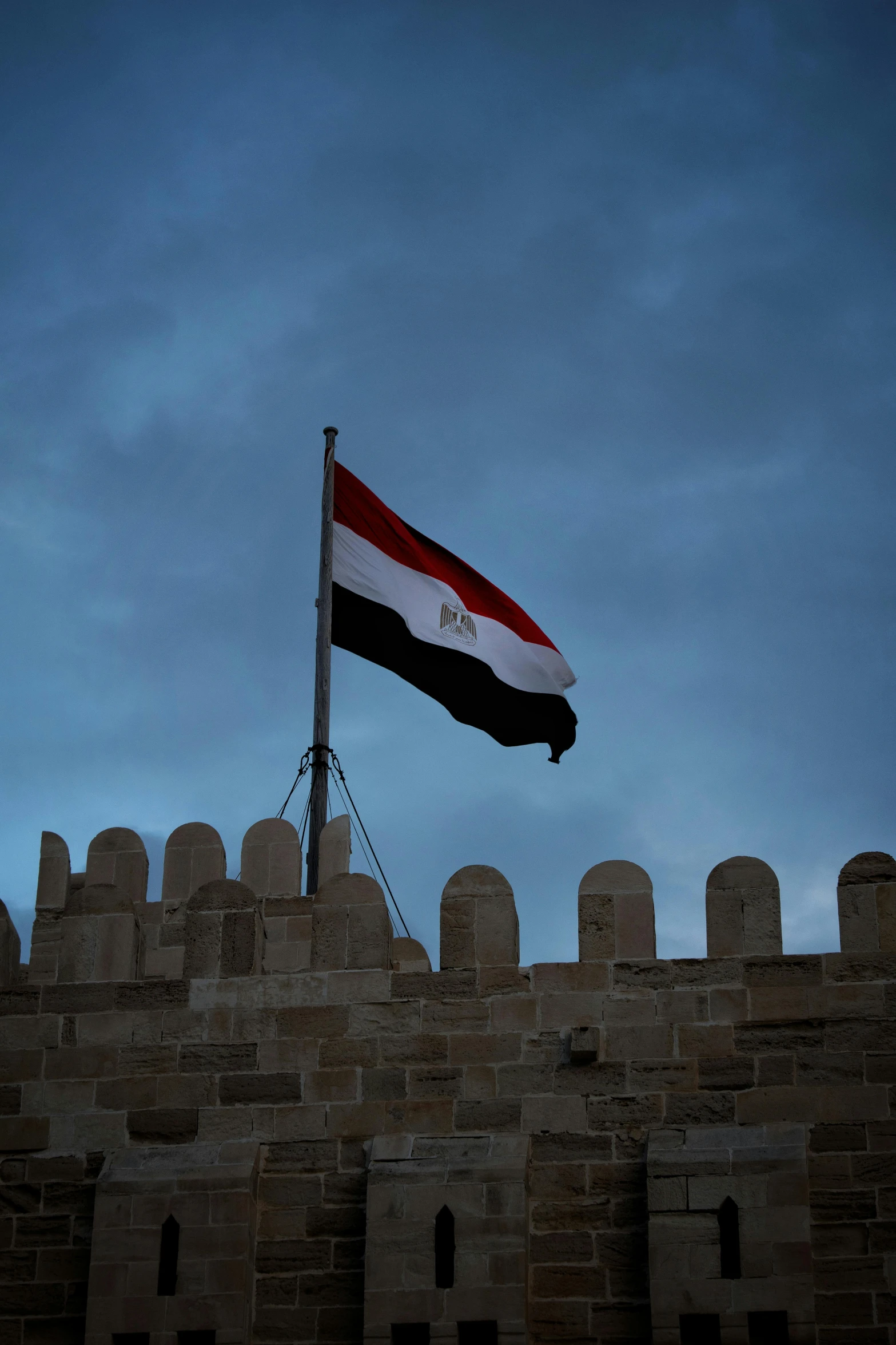 the flag of egypt flying on a tall brick building