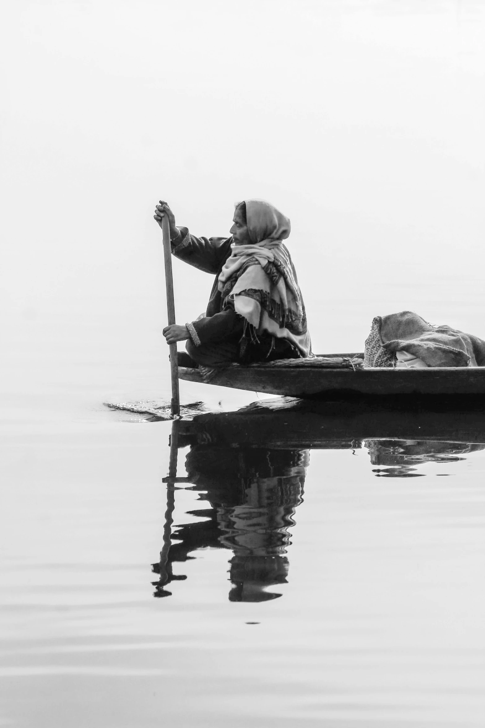 a man sitting on the front end of a canoe holding a paddle