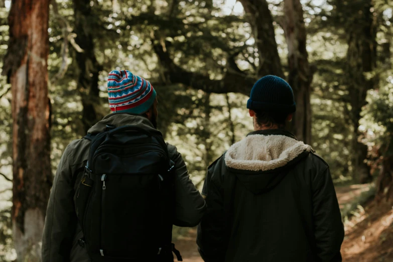 two people holding hands on a path in the woods