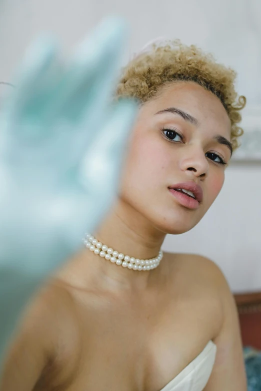 a close up of a person wearing a choker and pearls