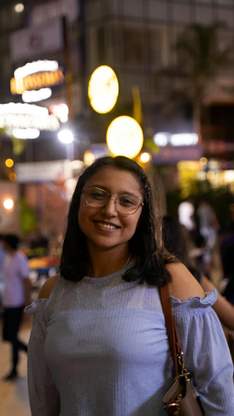 a woman standing on the sidewalk with many colorful lights in the background