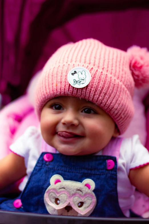 a smiling baby wearing pink and blue overalls