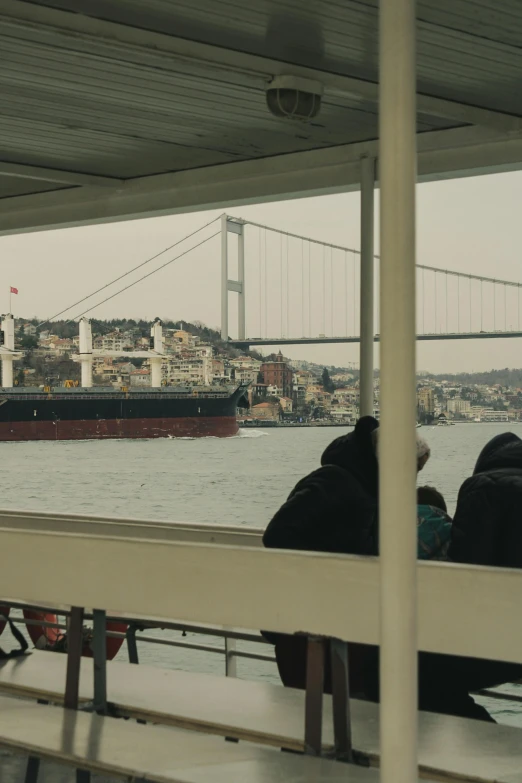 some people watching soing by the water near a big ship