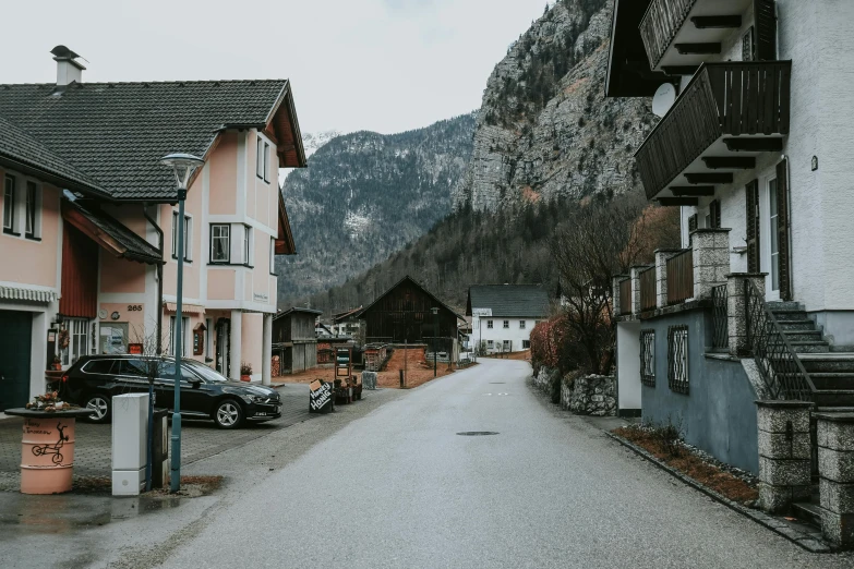 a street is lined with parked cars in front of mountains