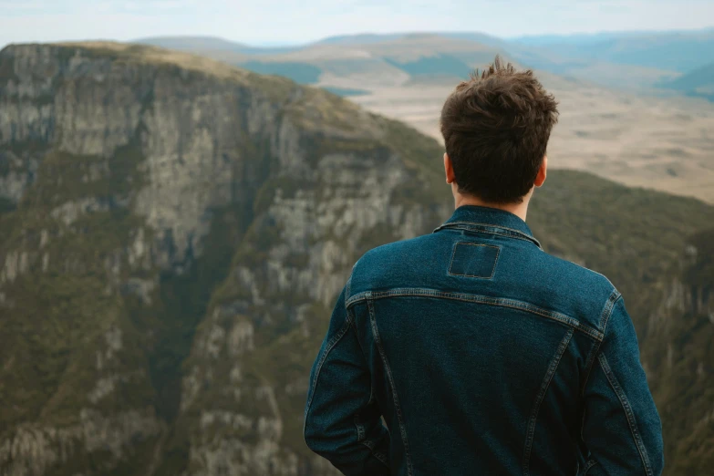 a man looks out over the mountains from a high point