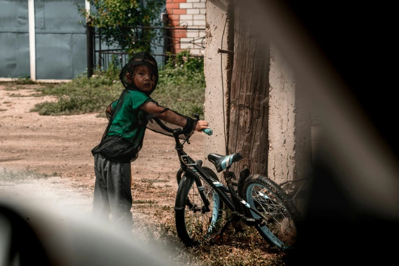 a little  with a bicycle near a building