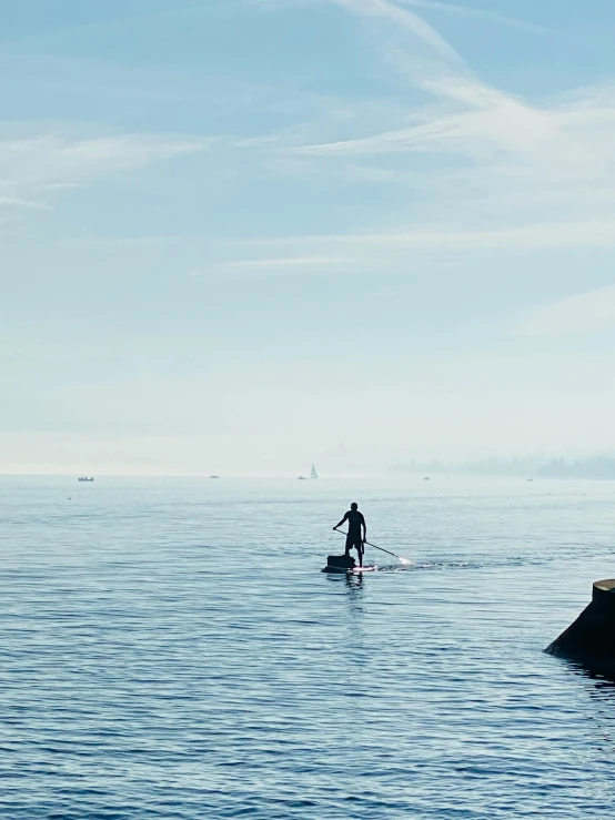 man in black wet suit riding a surfboard near lighthouse