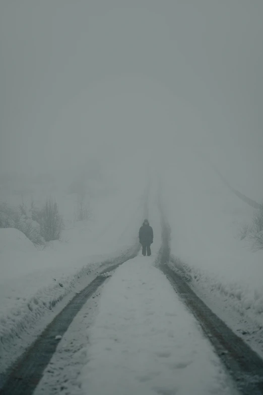 two people standing on a snow covered road with no vehicles