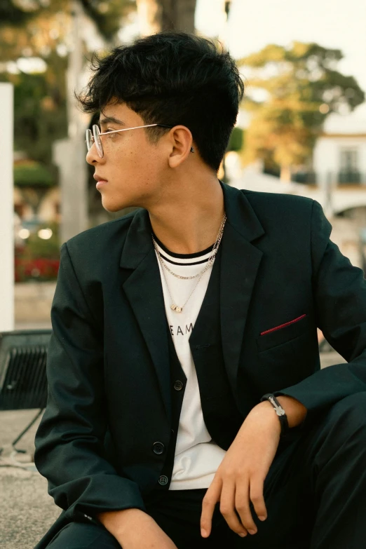 a young man in a suit sitting on the ground