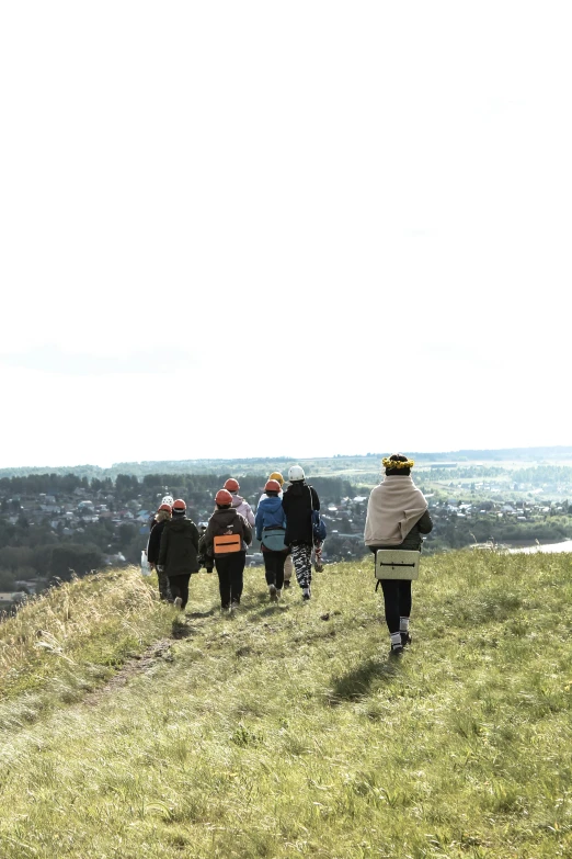 people standing on a grassy hillside looking over the city