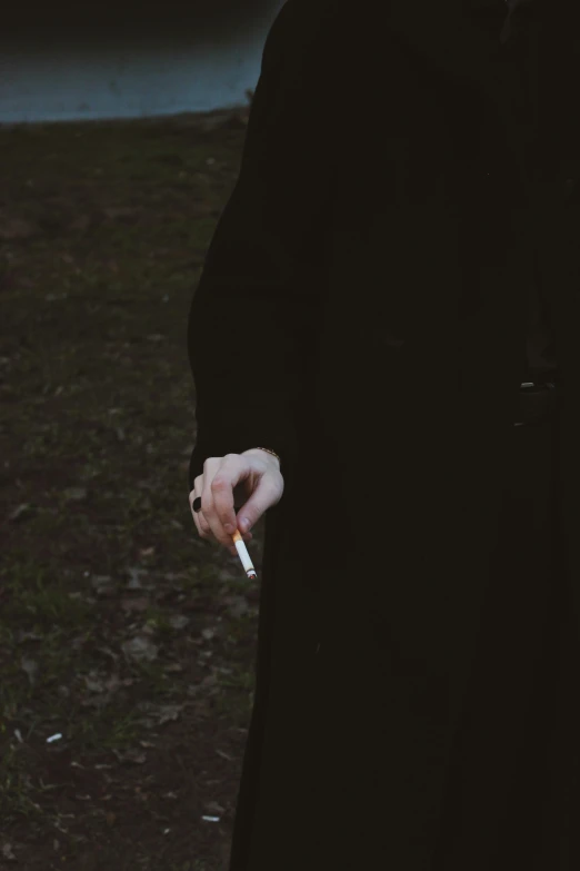 a man in a black coat is smoking a cigarette