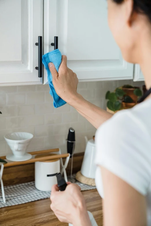 woman using a disposable microfit cleaner on cabinets