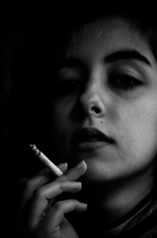 a woman holds a cigarette and looks into the camera