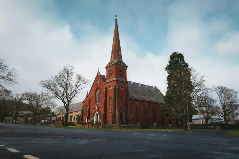 a brick church with a tall steeple against a cloudy sky