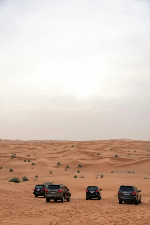 four vehicles parked on top of a sandy hill