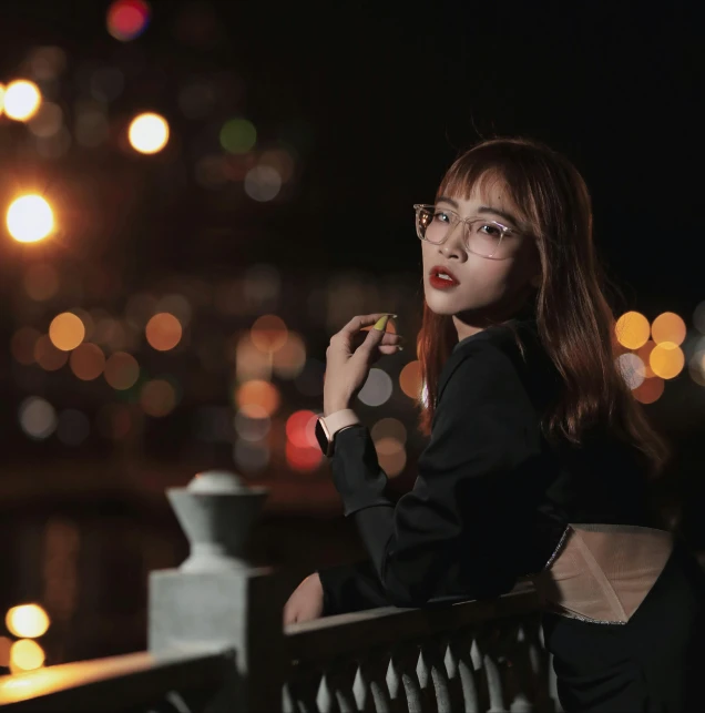 a woman smoking and wearing glasses in front of a city at night