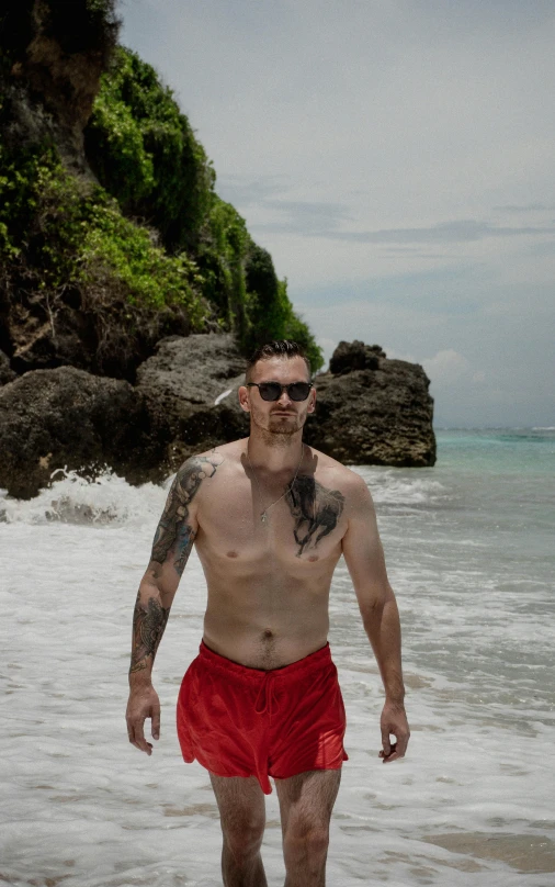 a man in swimming trunks walking through the ocean