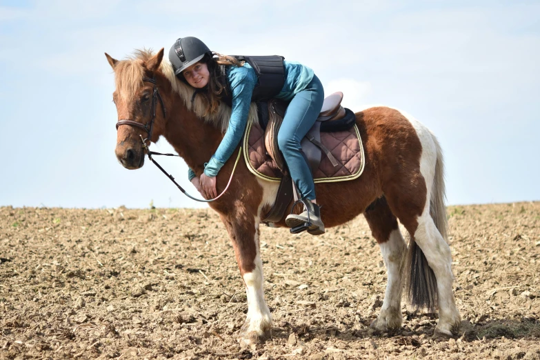 a person in jeans and boots sitting on a brown and white horse