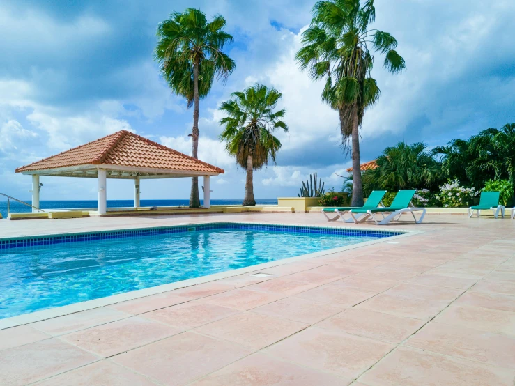 a swimming pool has chairs around it and trees