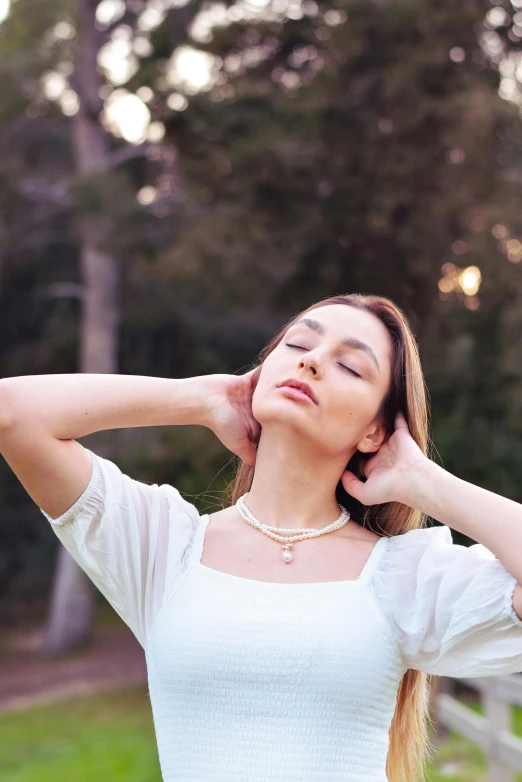 a woman sitting in front of a tree while holding her hand to her head