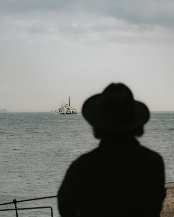 man looking out over the water at a boat