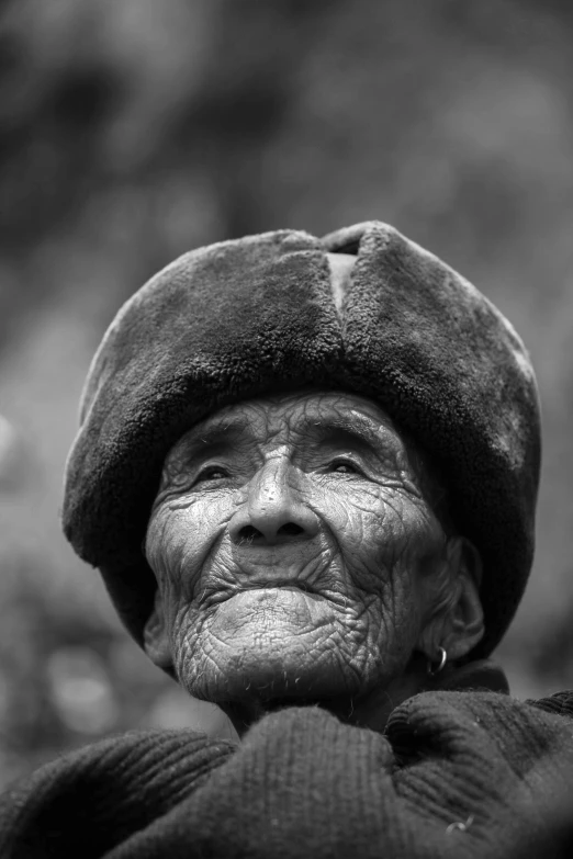 a smiling woman with a hat on and a tree in the background