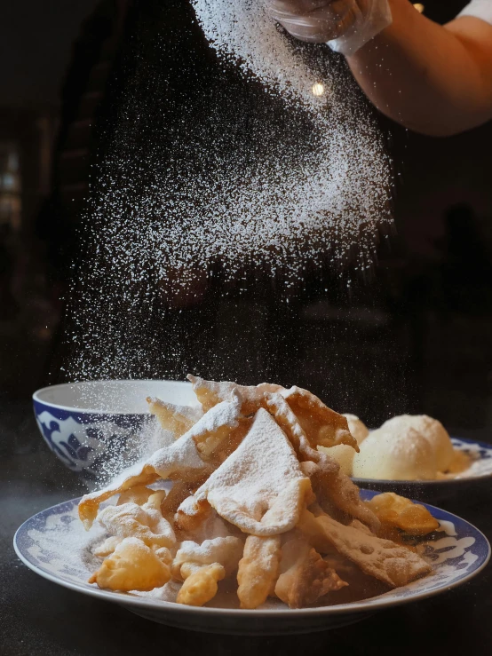 food being sprinkled from a spoon on a plate