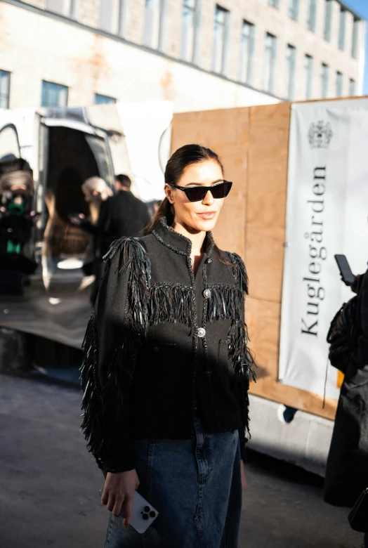 a woman in a fringed black jacket and sunglasses