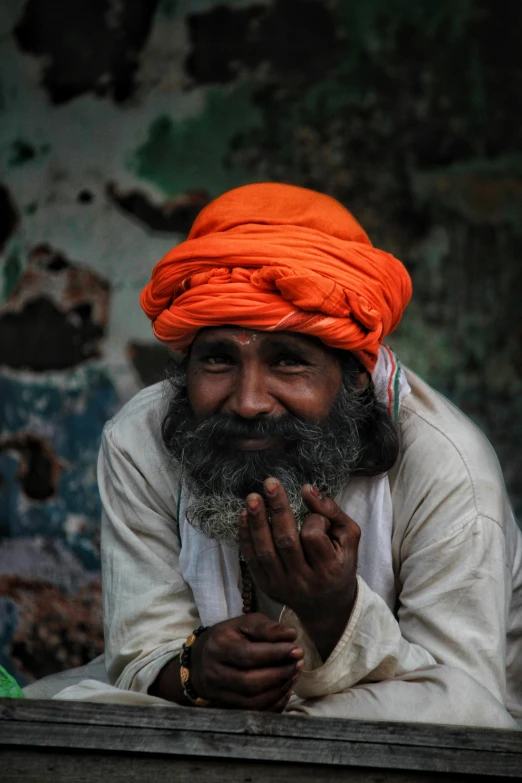 man with turban and beard sitting on a wooden floor