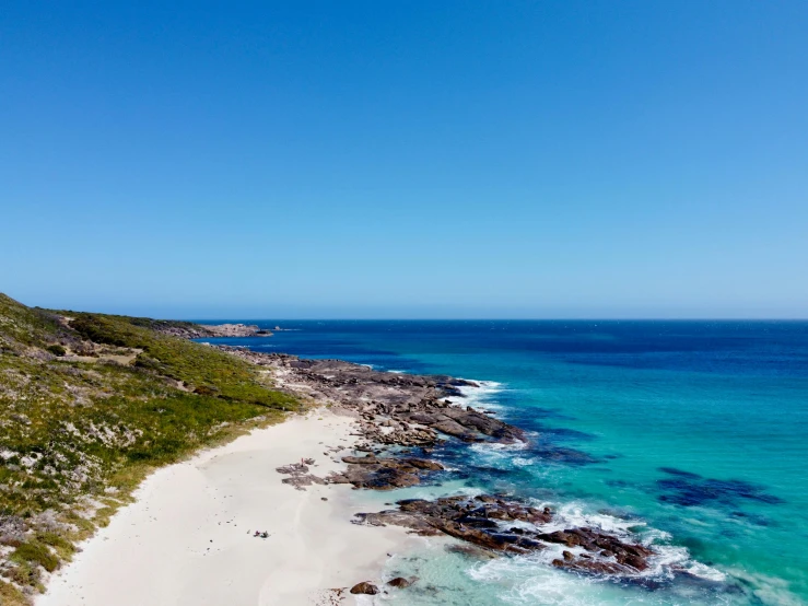 a beach and a steep hill with a body of water on the side of it