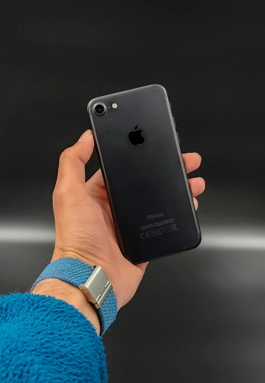 a hand holds a black iphone in front of the camera