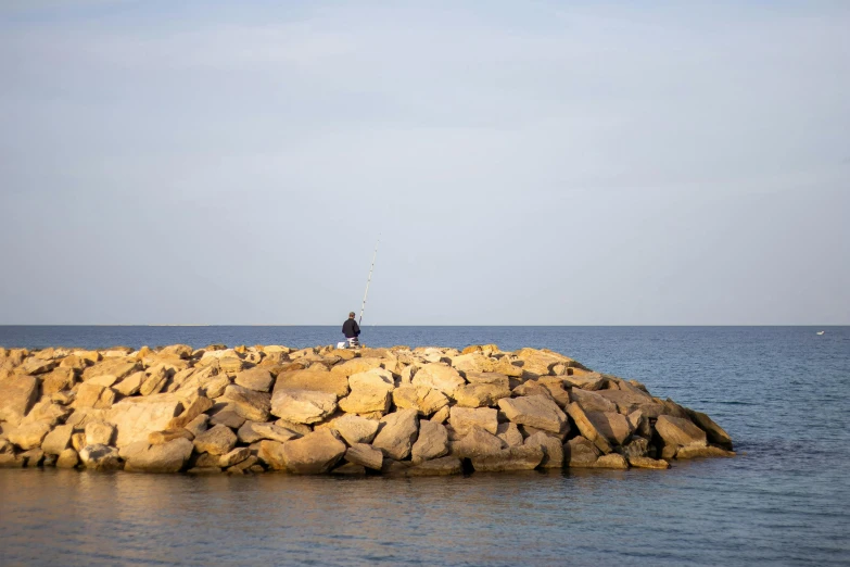 a person standing on top of a pile of rocks next to the ocean