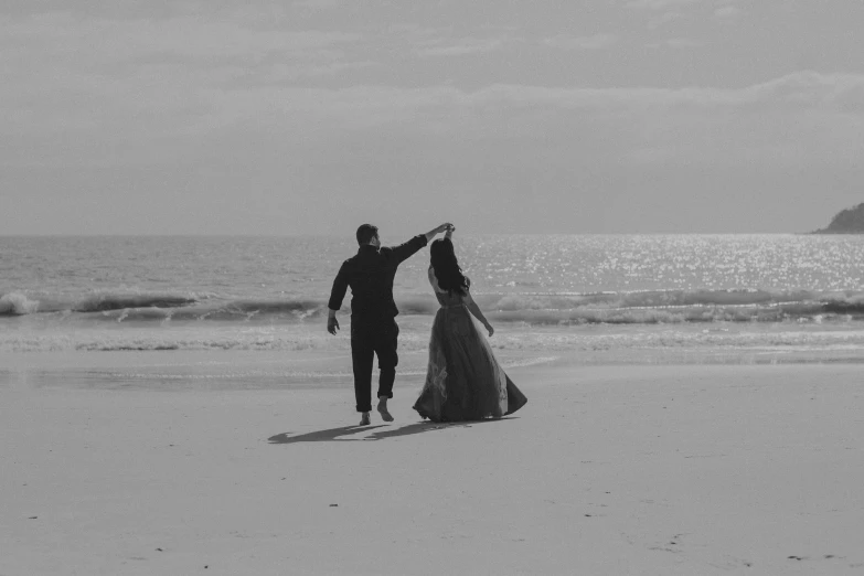 a couple is walking on the beach at sunset