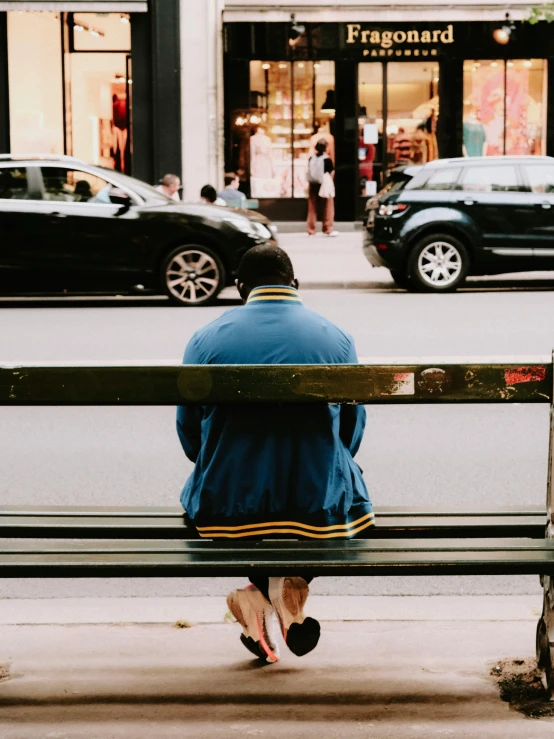 the man is sitting on a bench watching traffic