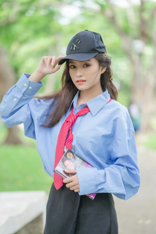 a woman in a suit and a baseball cap is holding her hat and posing for the camera