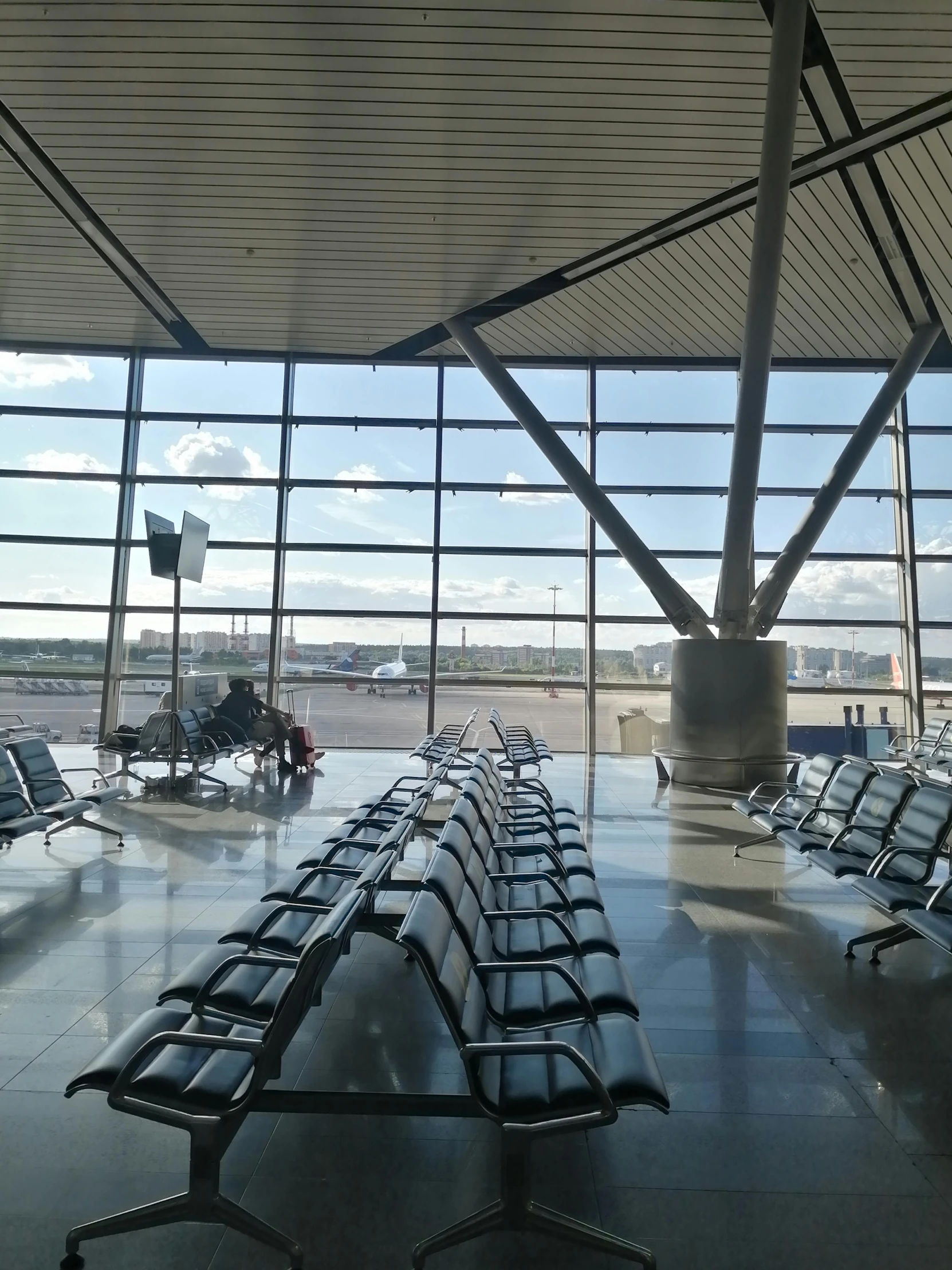 some seats inside of an airport with a plane