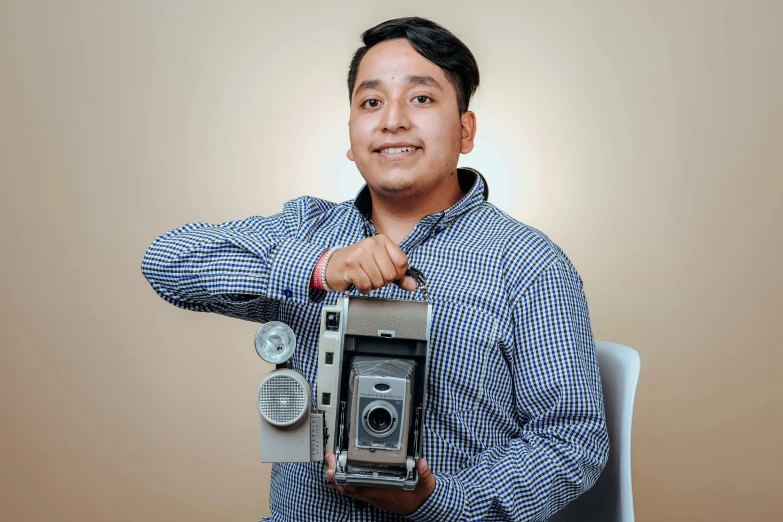 a man poses while holding a small camera