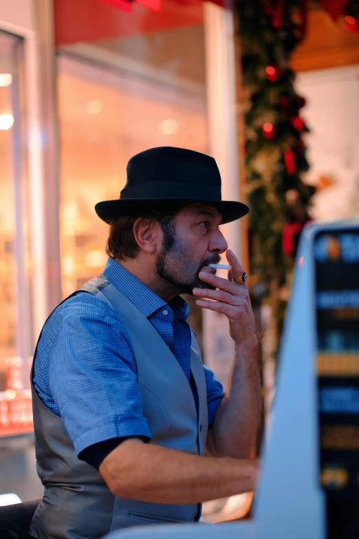 man sitting at table smoking cigarette looking into distance