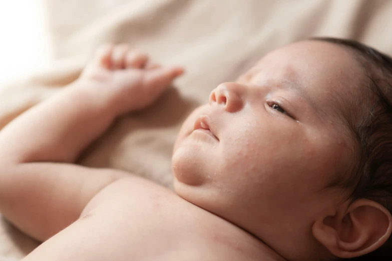 a baby with a tiny nose sleeping on a bed