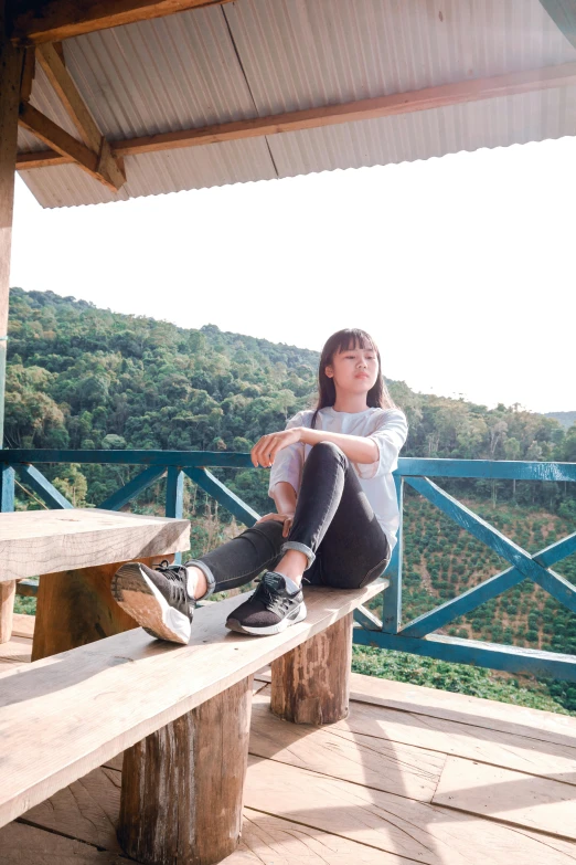 a woman sitting on a wooden bench with her legs crossed