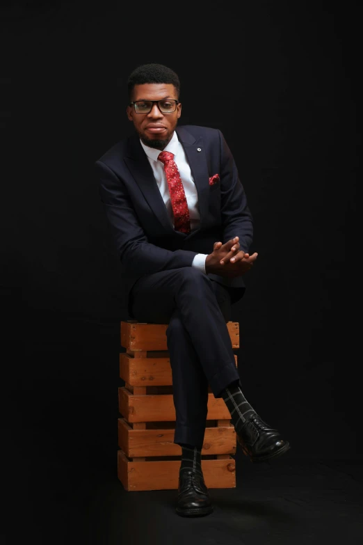 man sitting on a wood box and wearing a suit and tie