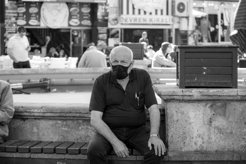 a man sitting on the side of the road wearing a mask