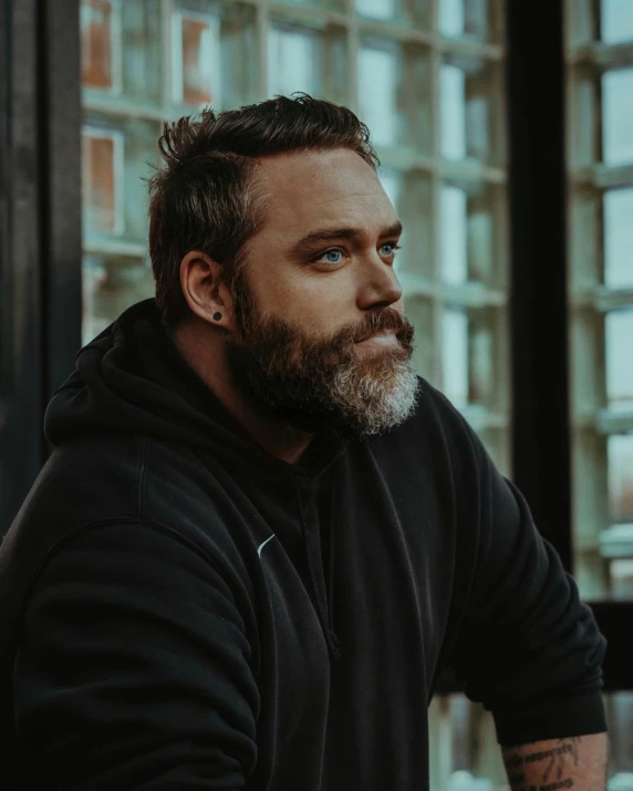 a man with a beard wearing black, sitting down