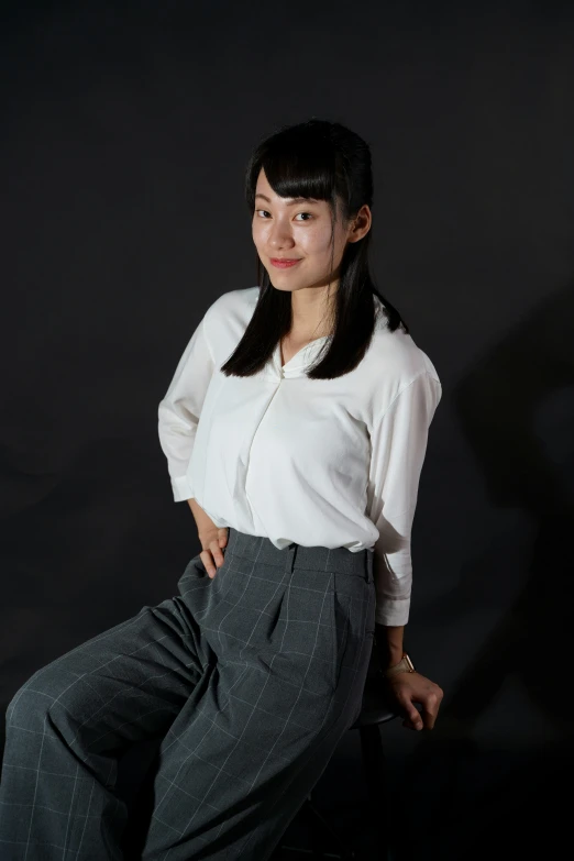 a woman poses in black pants and a white shirt