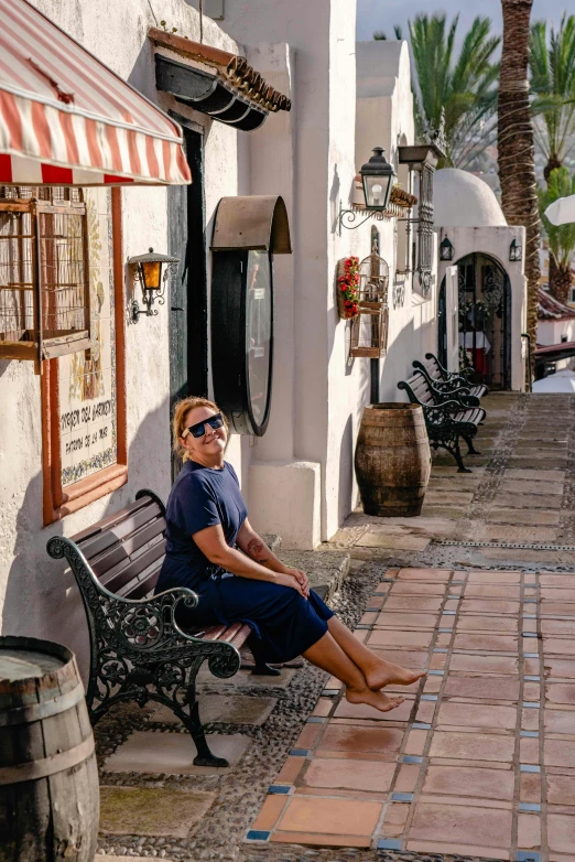 the woman is sitting on the bench near the building